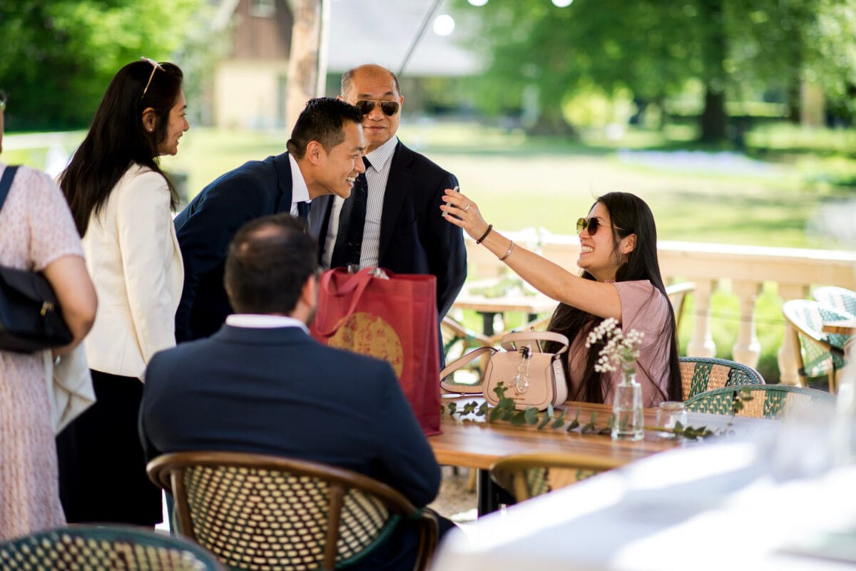 Vier mensen in gedeeltelijk genieten van een bruiloftsreceptie buiten kleding bij Bruiloft Nienoord, lachend en socialiserend tegen een zonnige, groene achtergrond.